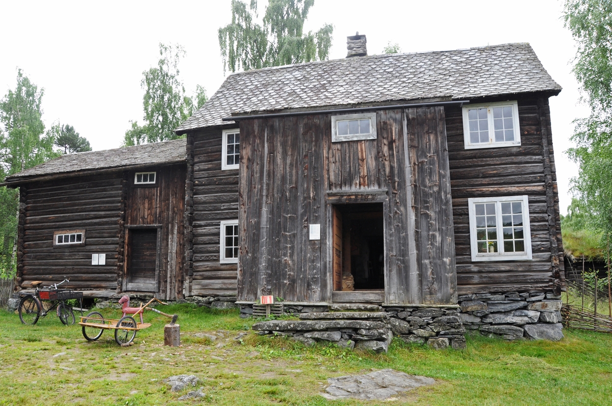 Bygning i to høgder, med sval og rosemåla dører.