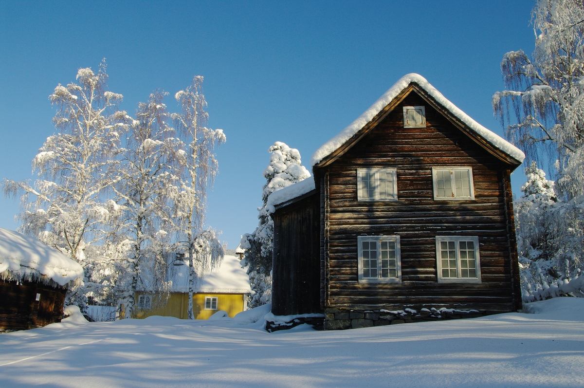 Bygning i to høgder, med sval og rosemåla dører.