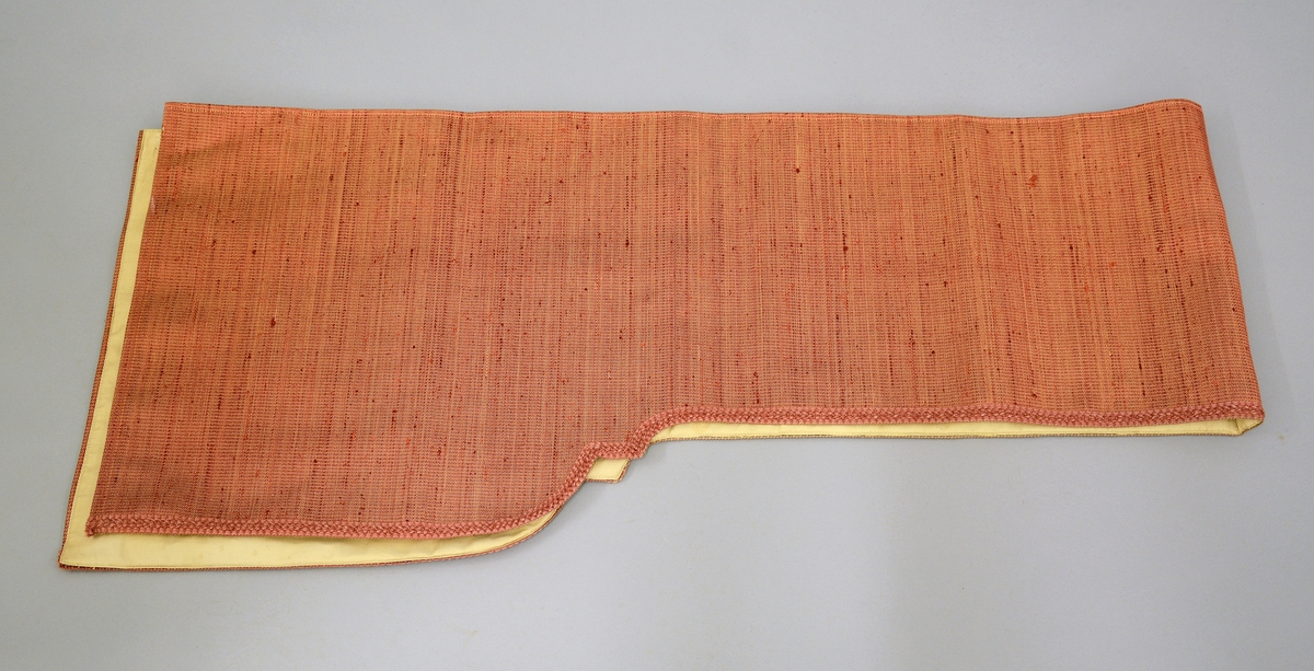 Gardin med kappe og stores. Rødorange gardin i bomull og syntetiskematerialer. Gardinen er fòret med beige bomullstøy. Gardinkappe i samme materiale. Rosa stores i bomull. Gardinen har hengt i spisesalen på Ulefos Hovedgaard.