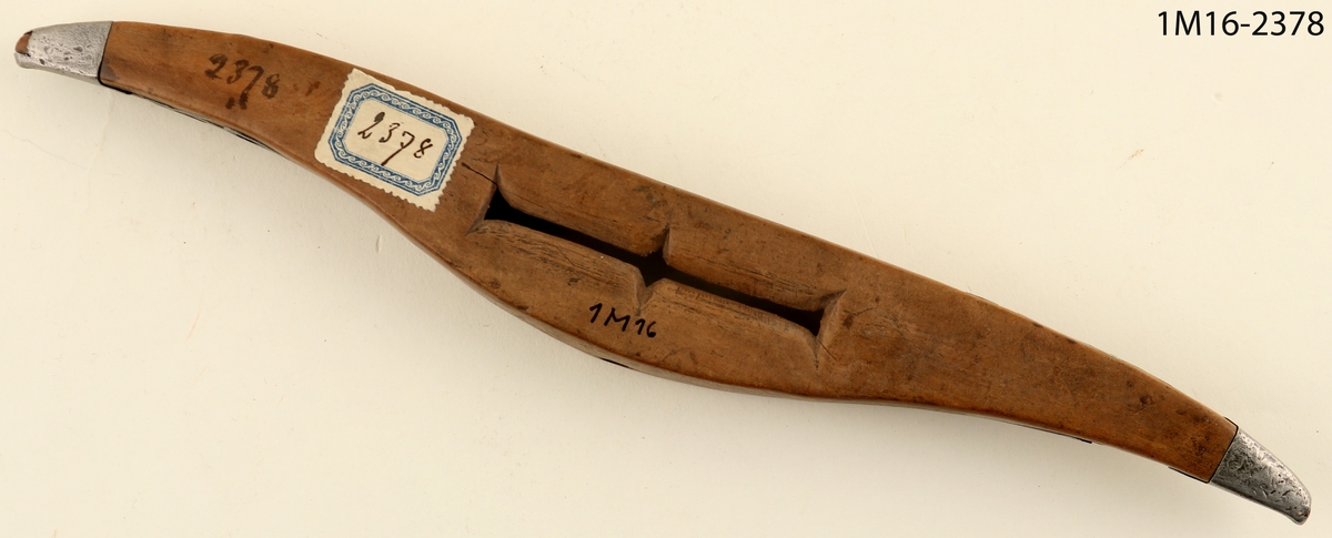 Vävskyttel med ornament av metall samt årtalet 1765.