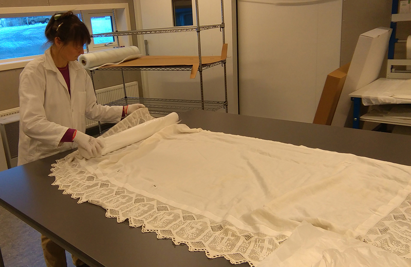 Teknisk konservator, Randa Arntzen, er i gang med å pakke en fasongsydd alterduk tilhørende Trøgstad bygdemuseum.