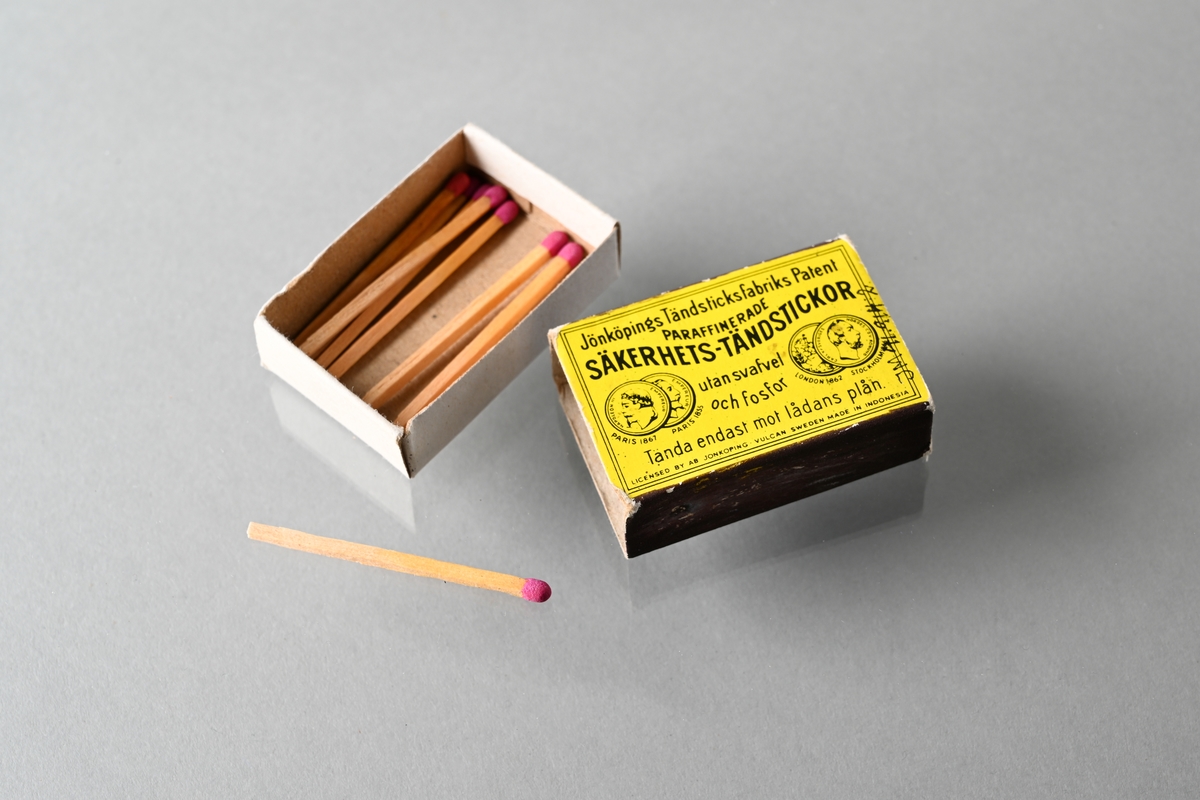 Tändsticksask bestående av innerask och ytterask. Ytteraskens ovansida är gul och har tryckt text: "Jönköpings Tändsticksfabriks Patent PARAFFINERADE SÄKERHETS-TÄNDSTICKOR utan svafvel och fosfor Tänd endast mot lådans plån LICENSED BY AB JÖNKÖPING-VULCAN SWEDEN MADE IN INDONESIA". På ytteraskens ovansida finns även tryckta bilder av medaljer från utställningar i Paris 1855 och 1867, och utställningar i London 1862 och Stockholm 1866. Ytteraskens undersida är blå. Asken innehåller nio oanvända tändstickor.

JM 41914:1, innerask
JM 41914:2, ytterask