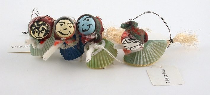 Figurer av vita piprensare. Huvud av papperkula. Sitter på kvast av piprensare och borst. Schalett i rutigt tyg, kjol av knäckformar. 
:1-2: Blå. 
:3 Turkos. 
:4-5 Grön. 
:6 Gul. 
:1-6 Tråd för upphängning.