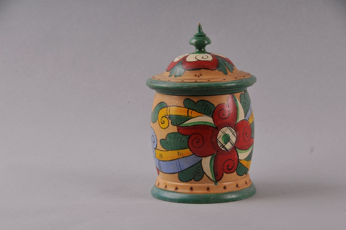 Dreia skrin med lok, måla dekor på lakkera overflate. Påskrift er svidd inn.