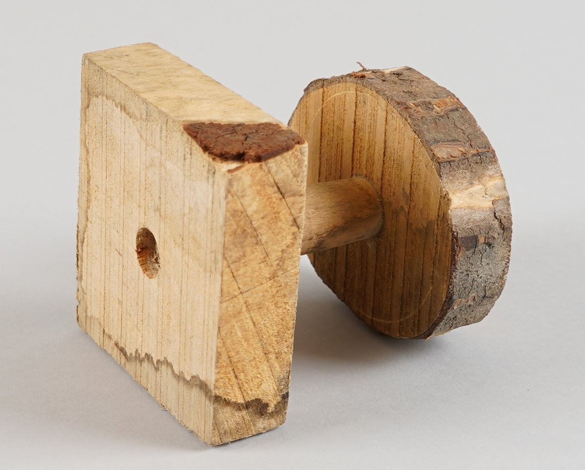 Emne til snelle (som er del av tein til hjulrokk). Truleg klar til dreiing. Eit dreia stykkje er sett ned i ein firekanta kloss (med rissa sirkel på oppsida) i eine enda og ein oval forma kloss med bark utanpå i andre enda (med rissa sirkel på nedsida). Det er hol gjennom alle tre delane i senter.