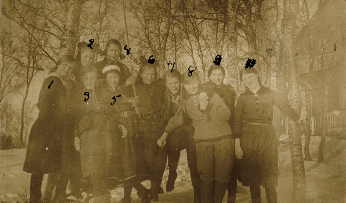 Portrettfotografi av ei gruppe unge jenter på en vei utenfor et hus.