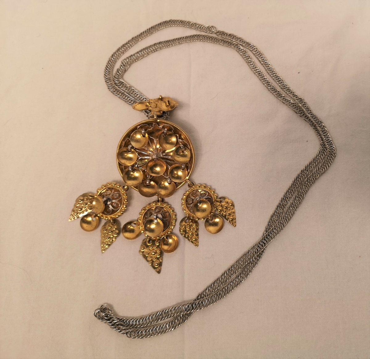 Lok med filigransrose.I nedrekanten heng tre mindre filigransroser med eit rombelauv i midten og eit skållauv på kvar side. Stempel PA 8. laga i Bergen i 1808.Sølja heng i ei flatlekkje.