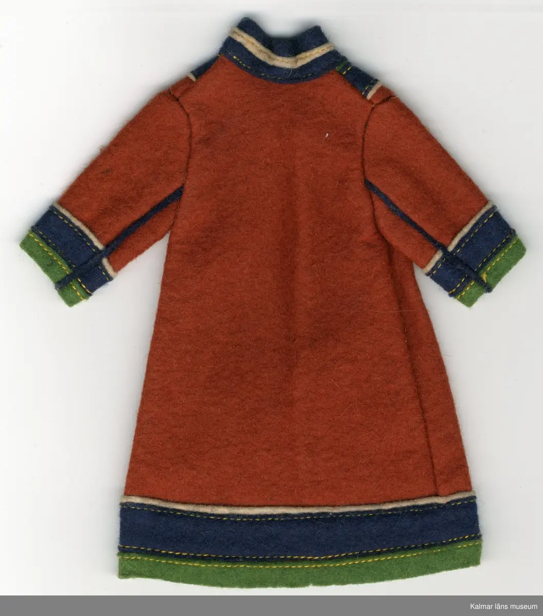 KLM 28082:292:1-3 Samekolt, dockkolt, 3 stycken, av textil, ylle. Lång kolt, utan öppning, brun, med grön, mörkblå och vit garnering. Nertill på ärm och koltens fåll, tygränder, lodräta, vit, mörkblå och grön, i nämnd ordning. Längs ärm, två blåa ränder i tyg, passepoalsydda. Krage, blå, hög i nacke, med vit tygrand, framtill, v-krage, i grönt, blått och vitt tyg. Del av samisk nationaldräkt.