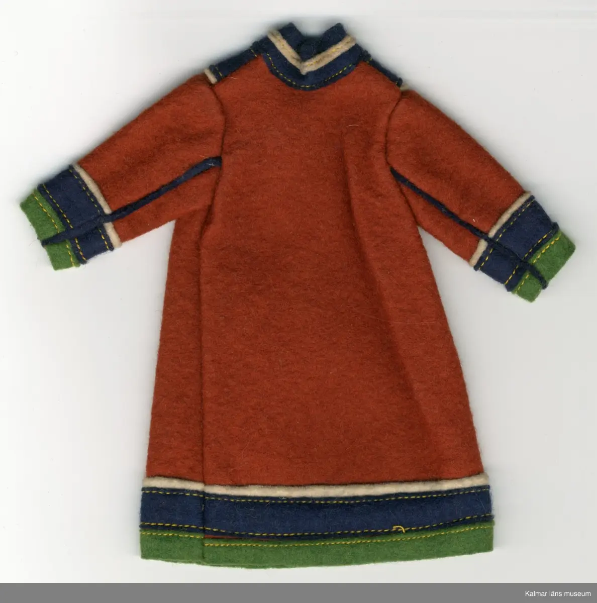 KLM 28082:292:1-3 Samekolt, dockkolt, 3 stycken, av textil, ylle. Lång kolt, utan öppning, brun, med grön, mörkblå och vit garnering. Nertill på ärm och koltens fåll, tygränder, lodräta, vit, mörkblå och grön, i nämnd ordning. Längs ärm, två blåa ränder i tyg, passepoalsydda. Krage, blå, hög i nacke, med vit tygrand, framtill, v-krage, i grönt, blått och vitt tyg. Del av samisk nationaldräkt.