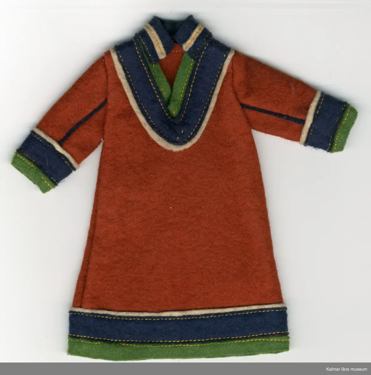 KLM 28082:292:1-3 Samekolt, dockkolt, 3 stycken, av textil, ylle. Lång kolt, utan öppning, brun, med grön, mörkblå och vit garnering. Nertill på ärm och koltens fåll, tygränder, lodräta, vit, mörkblå och grön, i nämnd ordning. Längs ärm, två blåa ränder i tyg, passepoalsydda. Krage, blå, hög i nacke, med vit tygrand, framtill, v-krage, i grönt, blått och vitt tyg. Del av samisk nationaldräkt.