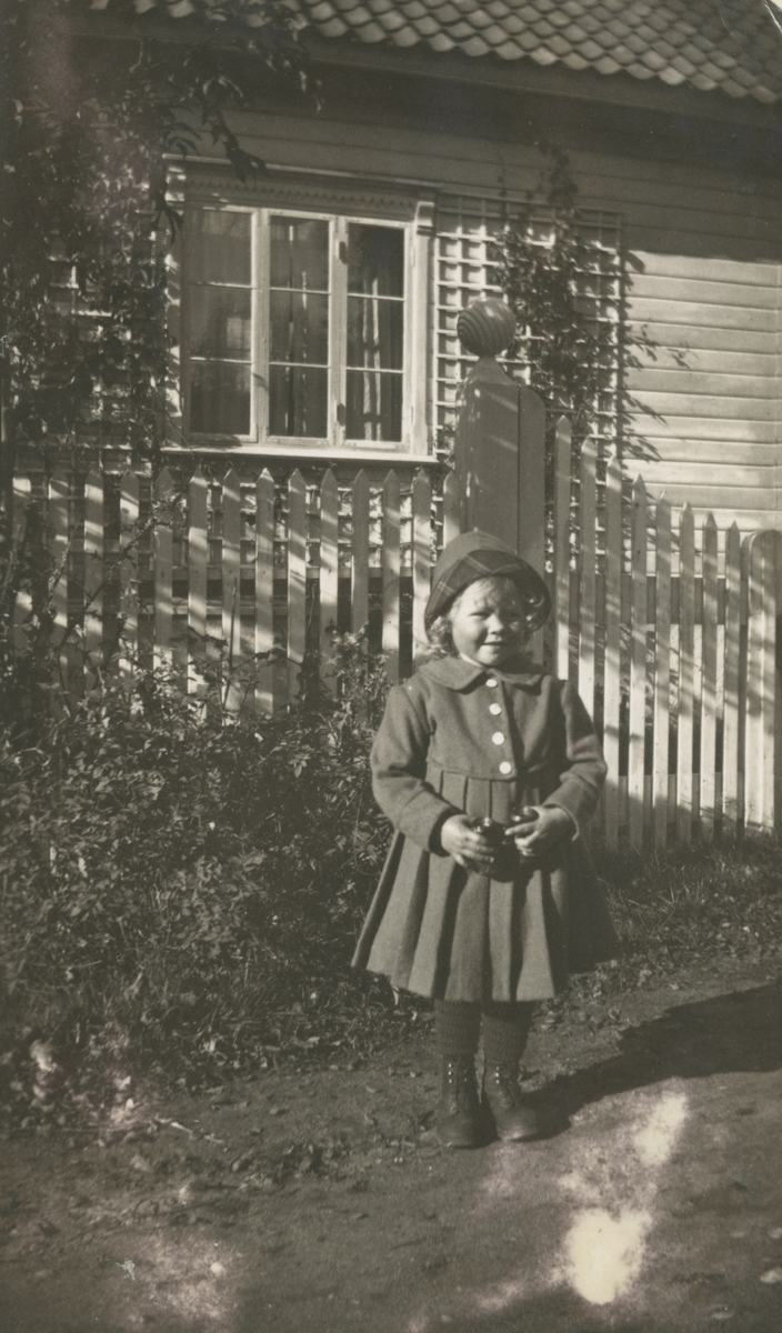 Portrettfotografi av ei jente foran et hus.