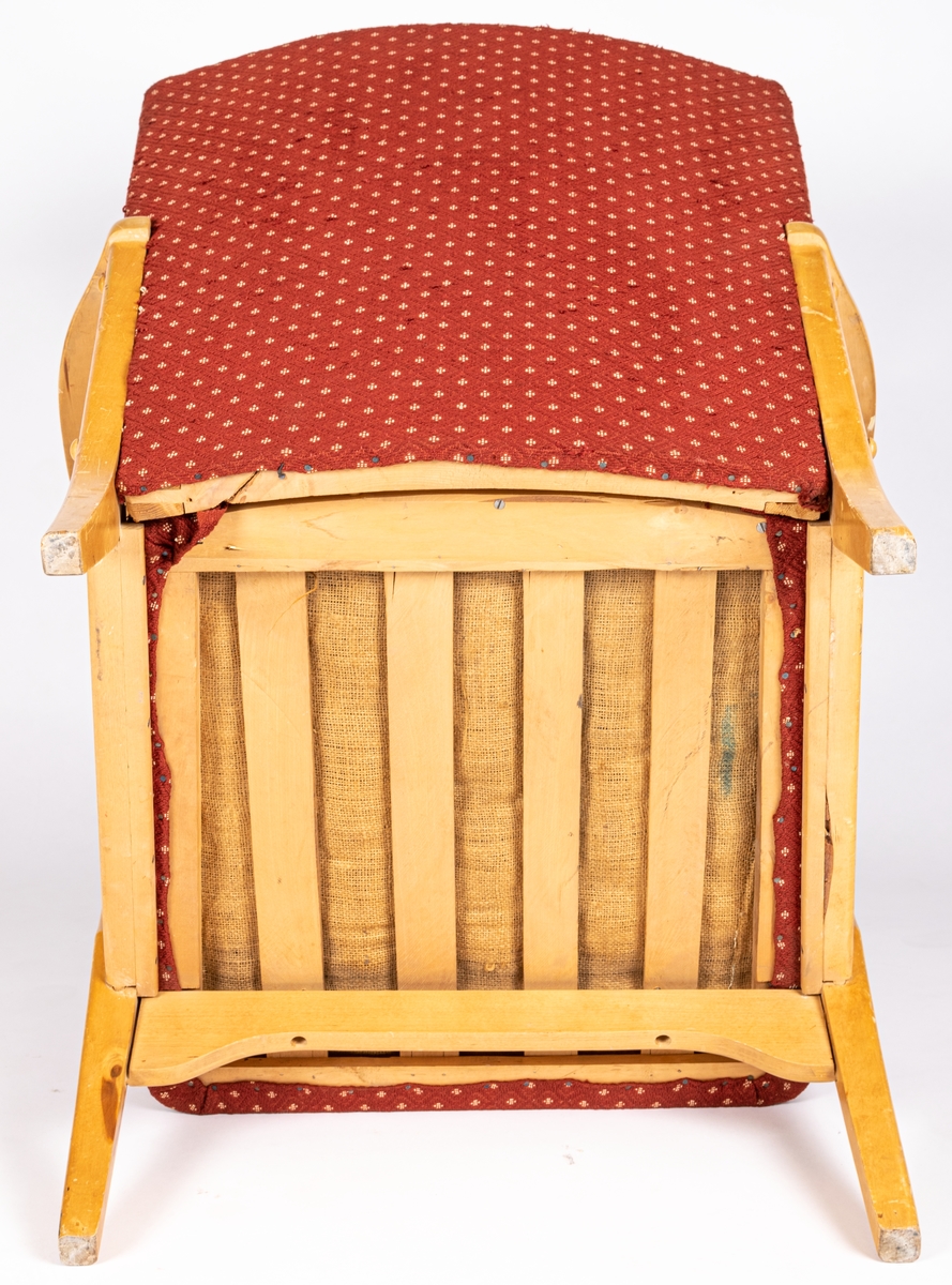 Katalogkort: Fåtölj. Ljust träslag i armstöd och ben. Sits och ryggstöd klädda med mönstervävt tyg. Varp: röd. Inslag: rett, vitt. Gåsögonliknande mönster. Sitsens kant, kantad med snodd i rött och vitt. På stolsryggens framsida fanns ursprungligen 3 textilklädda knappar, varav en saknas.

h 80cm, b 66cm, dj 77cm