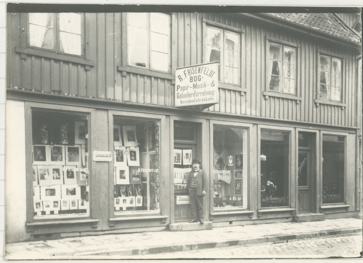 Dronningens gate 10. Frisenfeldt.
Ca. 1910. Fotograf har stått på utsiden av forretningen.
Detaljer: Herr Frisenfeldt på utsiden.
Historikk: Frisenfeldt var norges 3. oppstartede lektøysforretning. Lagt ned tidlig 2000-tall.