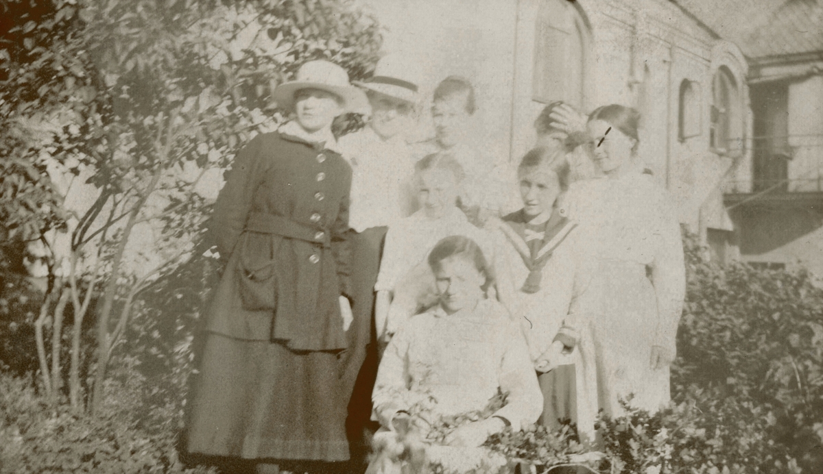 Portrettfotografi av ei gruppe kvinner og jenter i hagen foran et hus.