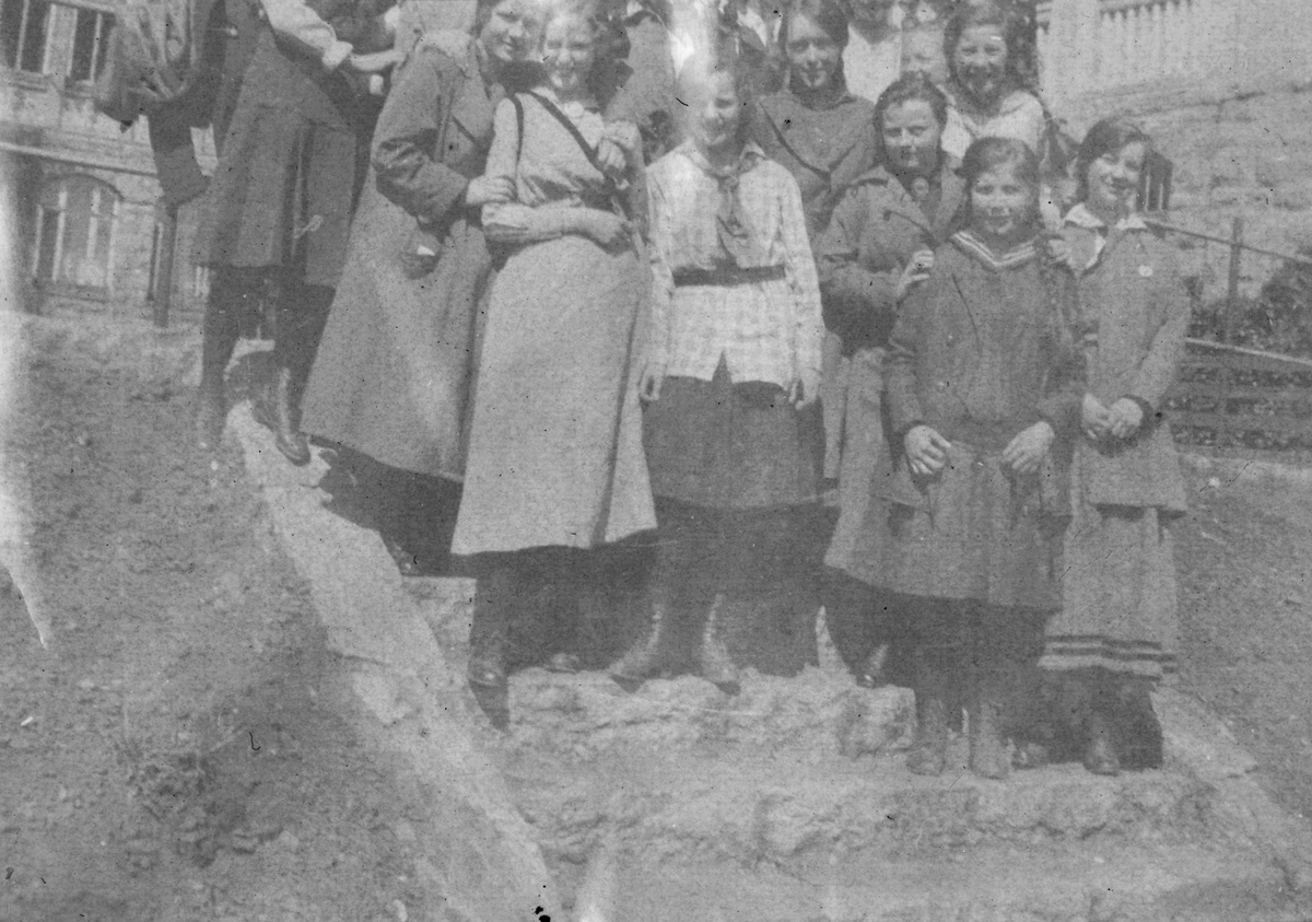 Portrettfotografi av ei gruppe unge jenter på ei trapp foran et hus.