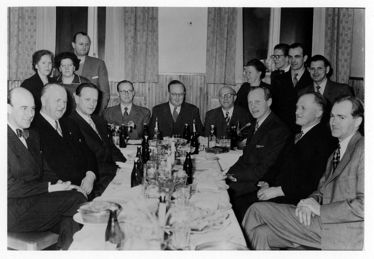 Gruppbild på arbetsledare på Suchards Chokladfabrik runt ett dukat bord. Sittande längst till vänster: Sven Pettersson.
