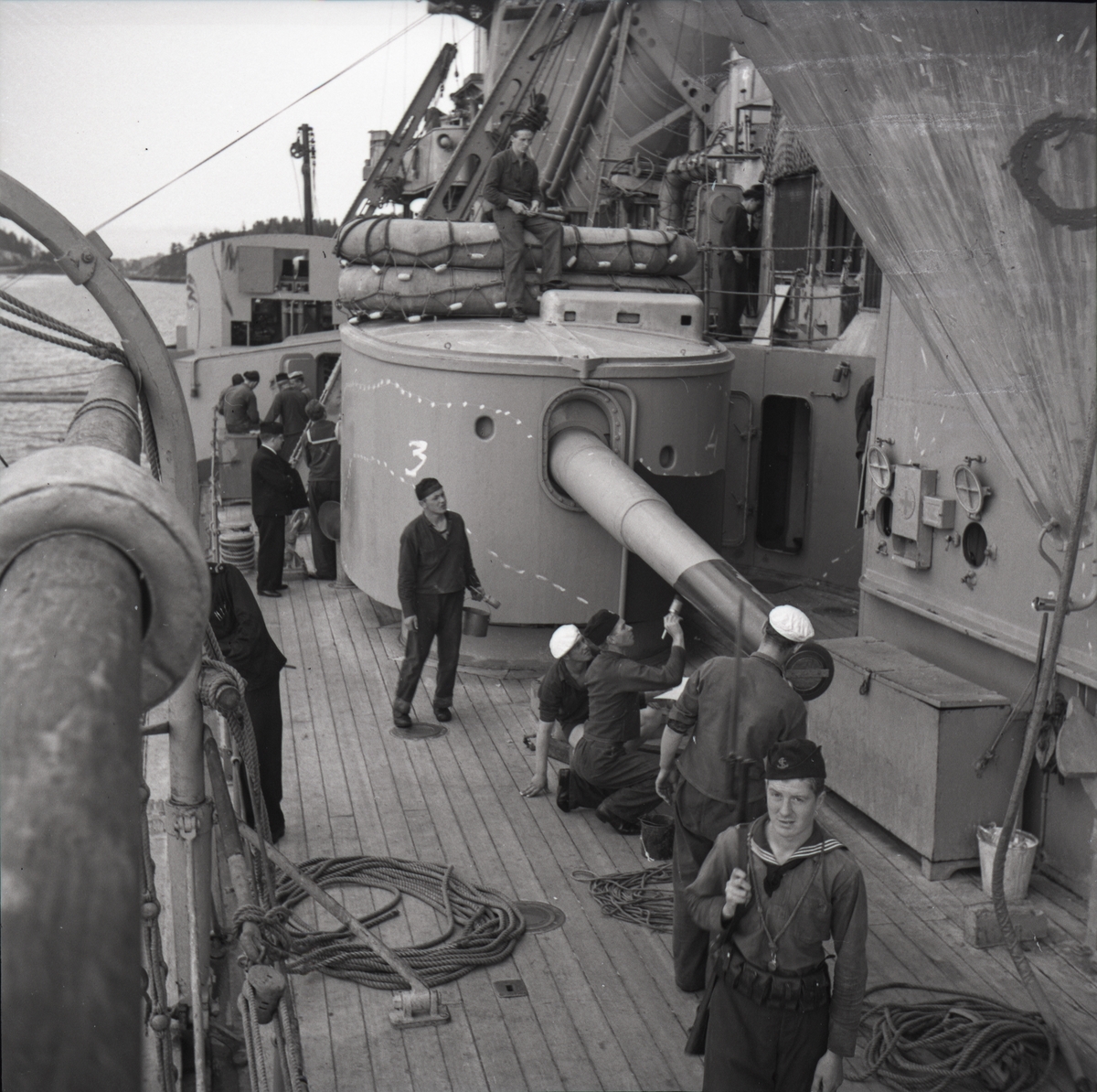 Foto från H.M.S. Gustaf V. Ett av 15 cm. tornen skyddsmålas.