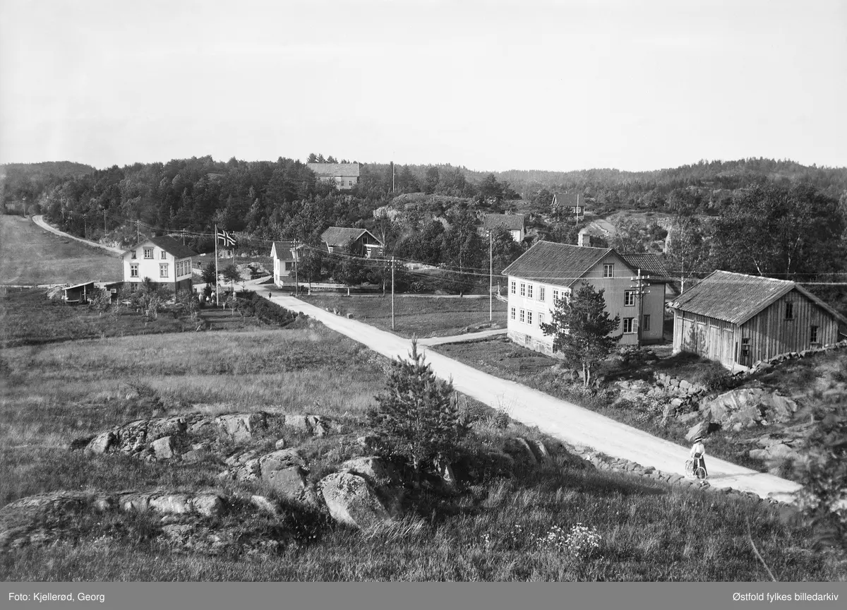 Øyestad sparebank i Arendal. Kvinne på sykkel. Gårdsbruk i bakgrunnen.