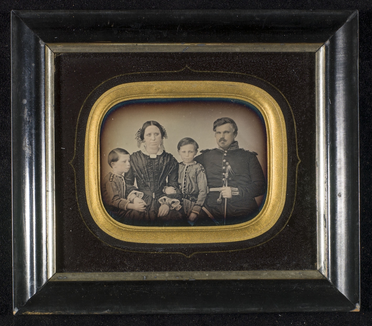 Daguerreotypi av familien Angell. Håndkolorerte hudtoner.
F.v.: Johannes Wiel Angell (1848-1882), Mathilde Angell f. Wiel (1819-1857), Knut Andreas Angell (1845-1828), artillerikaptein Cornelius Angell (1812-1874).

Et daguerreotypi viser motivet speilvendt. Men legg merke til uniformsjakkens knepping. Herreoverdeler har, etter tradisjonen, knappene på høgre side, og derfor vil de i et daguerreotypi vises på overdelens venstre side - speilvendt. Men uniformsjakken viser knappene på høgre side - altså ikke speilvendt. Det er derfor synnsynlig at dette er en refotografering av en original. Man har tatt ett bilde av et bilde! Se relaterte objekter under.