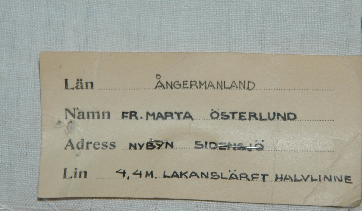 Varp av vitt bomullsgarn, inslag halvblekt 1 tr lingarn, tuskaft. Ena kortsidan sydd med glesa kaststygn, andra sidan ofållad.

Pappersetikett med uppgifter.

Varp: 24 tr/cm
Inslag: 20 tr/cm