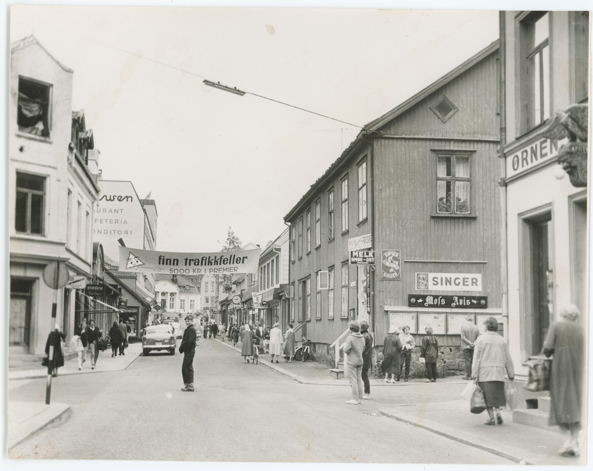  	
Dronningens gate. 1960. Mulig avisbilde.
Kommentar:	Fotograf har stått ved krysset Prinsens gate.	
Detaljer:	Til høyre deler av Apoteket Ørnen, Ullsteingården. 
Historikk: Alt på venstre side er endret i dag. Ullsteinsbygget ble erstattet med Moss Bygg/Vendo.

	




	
