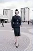 Fotomodellen (frilansande) Margareta Lindquist är klädd i jacka och
kjol samt uniformsmössa - båtmodell. Bilden tagen på Vällingby torg, 1960.