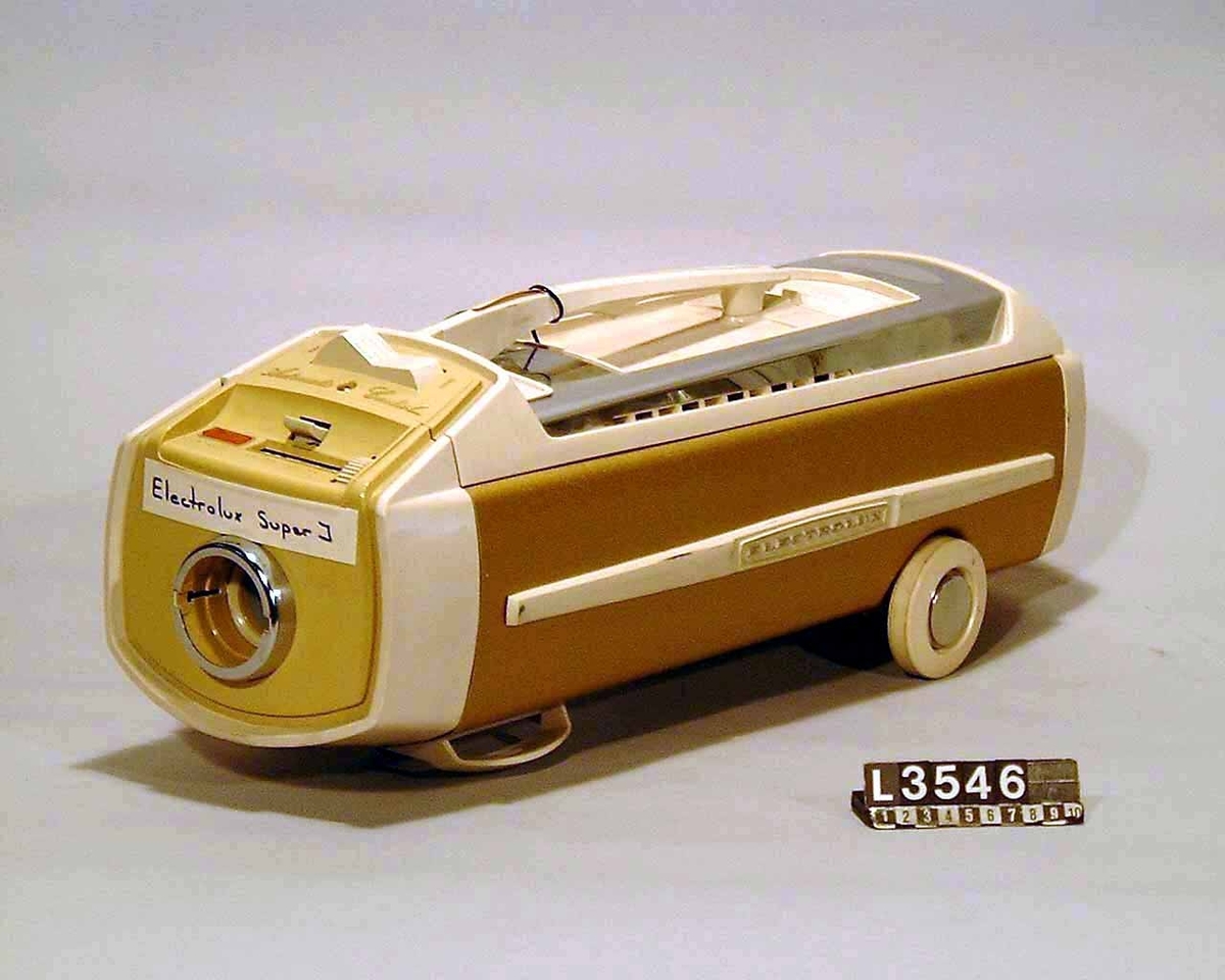 Guld metallic färgad dammsugare på hjul med fram och bakparti i vit plast. Stötdämpare i plast med Electrolux på sidan. Dammsugaren har kabelvinda, dammindikator samt dammbehållare i papper.