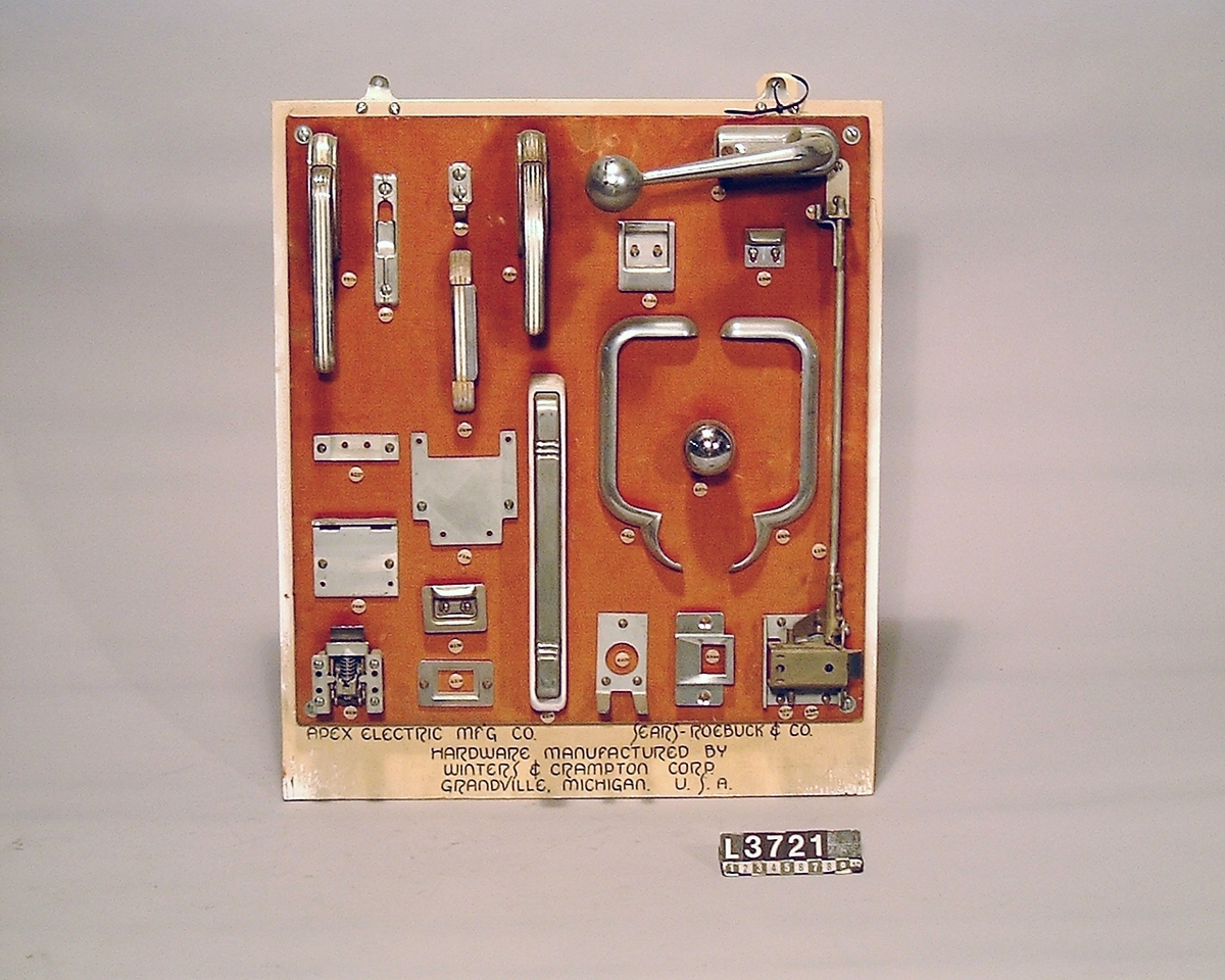 Gångjärn, handtag och låsannordningar till Sears-Roebucks kylskåp. Samtliga delar är uppsatta på en träplatta som är klädd med tyg. ADEX Electric mfg. Sears-Roebuck & Co.