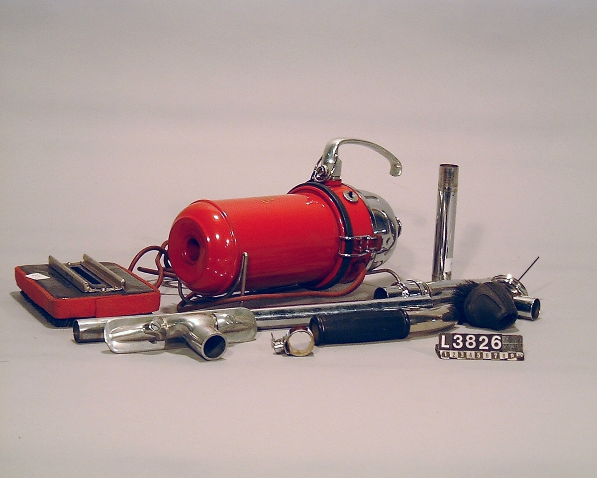 Handdammsugare, rödlakerad med blank bakdel. 2 skarvrör, 2 munstycken, fog- munstycke, möbelborste, extra handtag, samt en vätskespridare. Fast kabel. Apparaten är extrautrustad med medar. Hela apparaten är packad i en väska/koffert i kartong. Alla tillbehör finns.