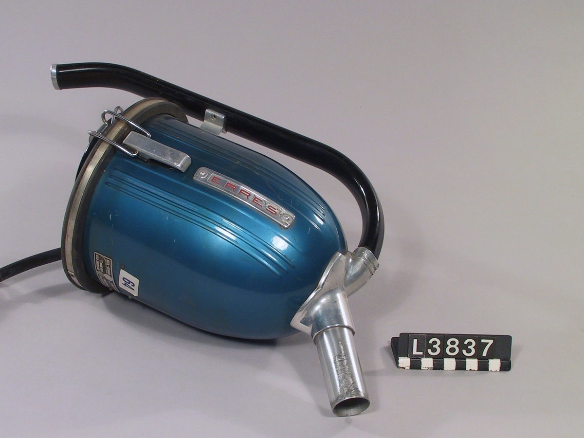 Handdammsugare i blå metallack. Bakstycke i svart bakelit. Skarvrör i aluminum. Golvmunstycke i metall, trä samt med borstring. Svart handtag.