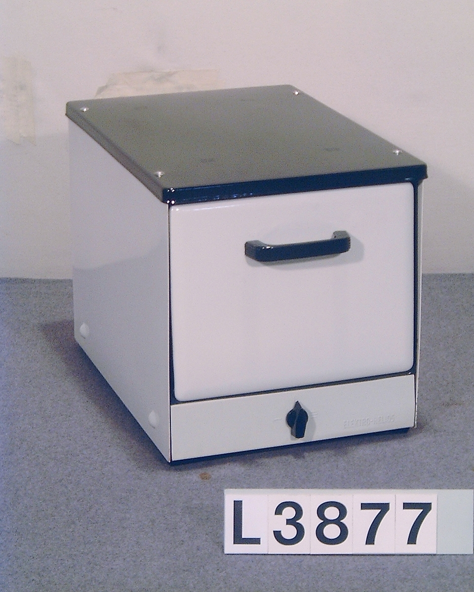 Bänkugn med vitemaljerad front, vitlakerade sidor och svartemaljerad topp. Strömställare med tre lägen. Ingen termostat. Plåtar finns och ugnen är något använd.