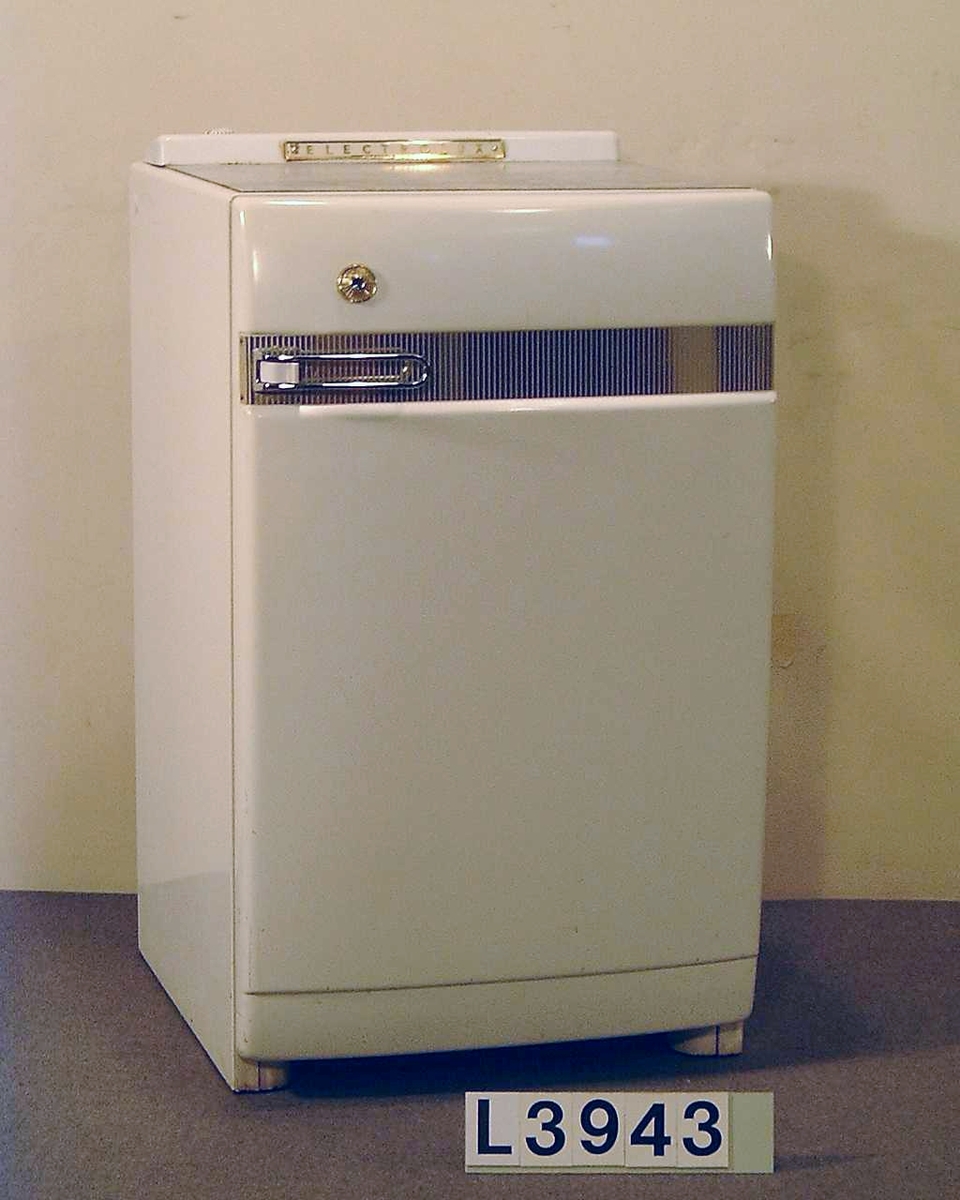 Table Top kylskåp värmedrivet av modell Golden Lux. På fronten löper ett band i gulmetall och handtaget är kromtat. Ovan på skåpet finns en linoleum skiva i gråspräckligt mönster. Kylskåpet har en volym på 110 liter.