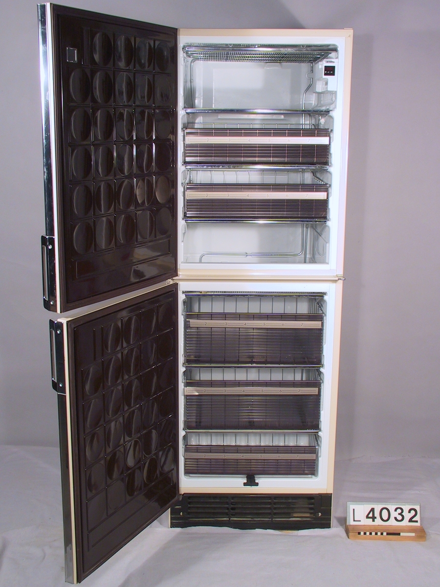 Tvådörrars frysskåp. Brun/vit inredning och på utsidanmandelstruktur. Lister och handtag är kromade. Elektronisk temperaturkontroll. Status: God.