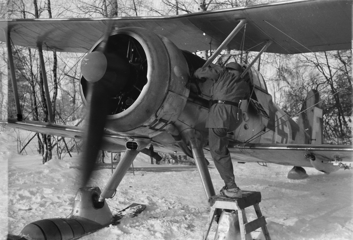 Flygplan Gloster Gladiator gul F görs klart för start. Mekaniker i arbete vid flygplansmotor. Vid F 19, Svenska frivilligkåren i Finland, 1940.