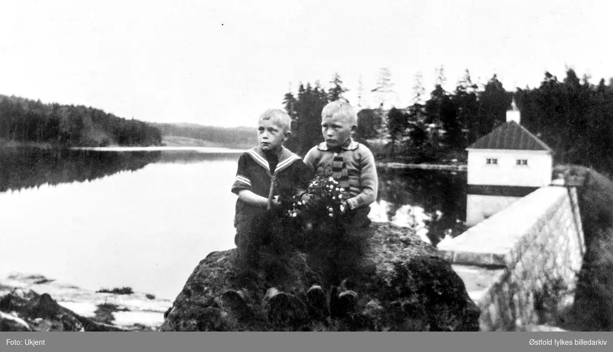 Vannbassenget i Borredalen i Rolvsøy, 1915-20? I forgrunnen brødrene Gundersen, sønner av Kristine og Martin Gundersen i Bjørndalen. Blomsterbukett med hvitveis.