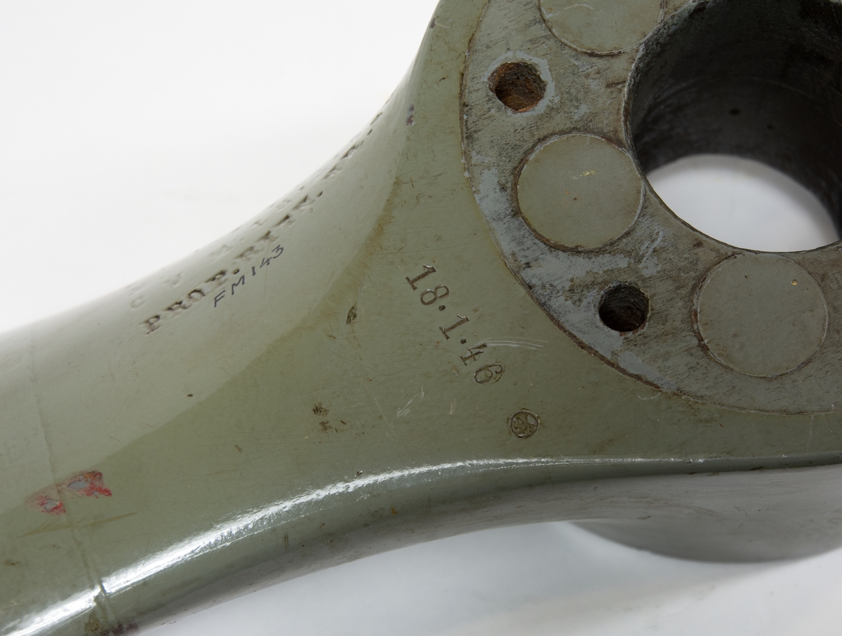 Tvåbladig träpropeller till SK 12. Propellern är målad grå och har skoning på bladen. Baksidan av propellerbladen är bruna. 
Propellern ligger i en trälåda. På locket står det att den tillhör SK 12/70.
