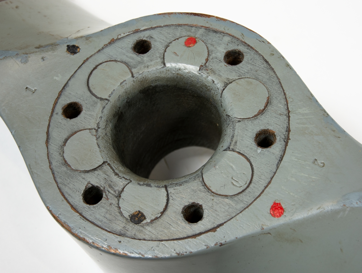 Tvåbladig träpropeller till SK 12. Propellern är målad grå och har skoning på bladen. Baksidan av propellerbladen är bruna. 
Propellern ligger i en trälåda. På locket står det att den tillhör SK 12/70.
