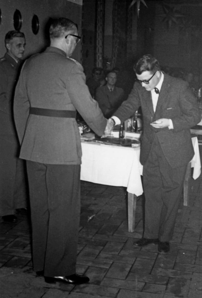 Matsalen, december 1961

Julkaffe efter Julvespern i Domkyrkan.

Bild 1. Regementschefen vid kaffebordet. Troligen syster Inez med ryggen mot oss.

Bild 2. Rustmästare Sven Jakobsson, soldatemföreståndaren diakon Per Johansson 1) och fanjunkare Åke Erbén.
1) Per "Pelle" Johansson var ett mycket uppskattat inslag i soldaternas vardag. Under övningar dök han ofta upp med sin folkvagnsbuss och sålde kaffe med bröd och godis. "Nu kommer Kak-Jesus! hördes i skogen."

Bild 3. Här avtackas konsulent G Kocths för sin insats vid regementet. Den 1 januari 1962 tillträder han ny tjänst vid Marinens Bergaskolor.