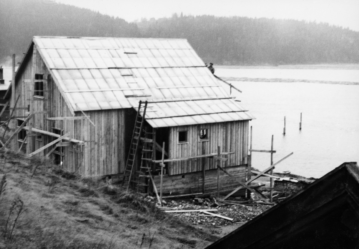 Den nye formannsboligen Glomma fellesfløtingsforening fikk reist ved Furuholmen i Varteig høsten 1954.  Fotografiet er tatt fra nord.  Det viser et halvannenetasjes hus, uført i bordkledd bindingsverk, med saltak som ennå ikke hadde fått noe permanent tekke.  På den ytre delen av den nordre langveggen er det et utbygg, sannsynligvis en entré/gang, med litt slakere takvinkel enn sjølve bygningskjernen.  Huset ligger med gavlen mot det nedenforliggende vassdraget.  I forgrunnen til høyre ser vi vindskia på et annet, eldre hus, antakelig en av bygningene på gardsbruket Nordre Furuholmen.  I bakgrunnen ser vi den stilleflytende delen av Glomma som ble kalt Storbogen, samt det skogkledde høydedraget på motsatt side, Hovden.  Huset ble bygd for daværende fløtingsformann ved Glennetangen lense, Johan Ringsrud. 

Reisinga av nye boliger, verkstedanlegg og kai ved Furuholmen var ledd i et arbeid for å kunne flytte virksomhet fra det gamle fløtingssenteret ved Nes, cirka to mil høyere opp i vassdraget, til Furuholmen.  Dette ble gjort fordi Furuholmen lå like ved Glennetangen, der hovedlensa for denne delen av vassdraget hadde ligget siden siste halvdel av 1930-åra.  Flyttinga av så vel funksjonærer som tekniske servicefunksjoner ble sluttført i 1958-59. 
