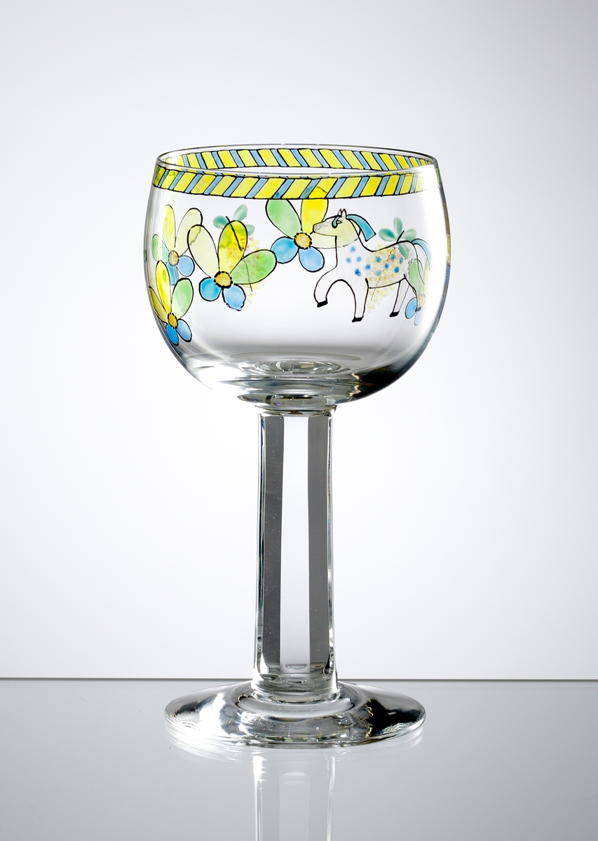 Vinglas av Gunnar Cyrén med generös kupa bemålad med "sverigemotiv" i form av människor och blommor i företrädelsevis blått och gult.
Facettslipat ben.