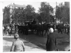 Processionen med likvagn på Storgatan i Tromsö, flankerade av matroser med gevär över axeln. En stor folksamling följer processionen.