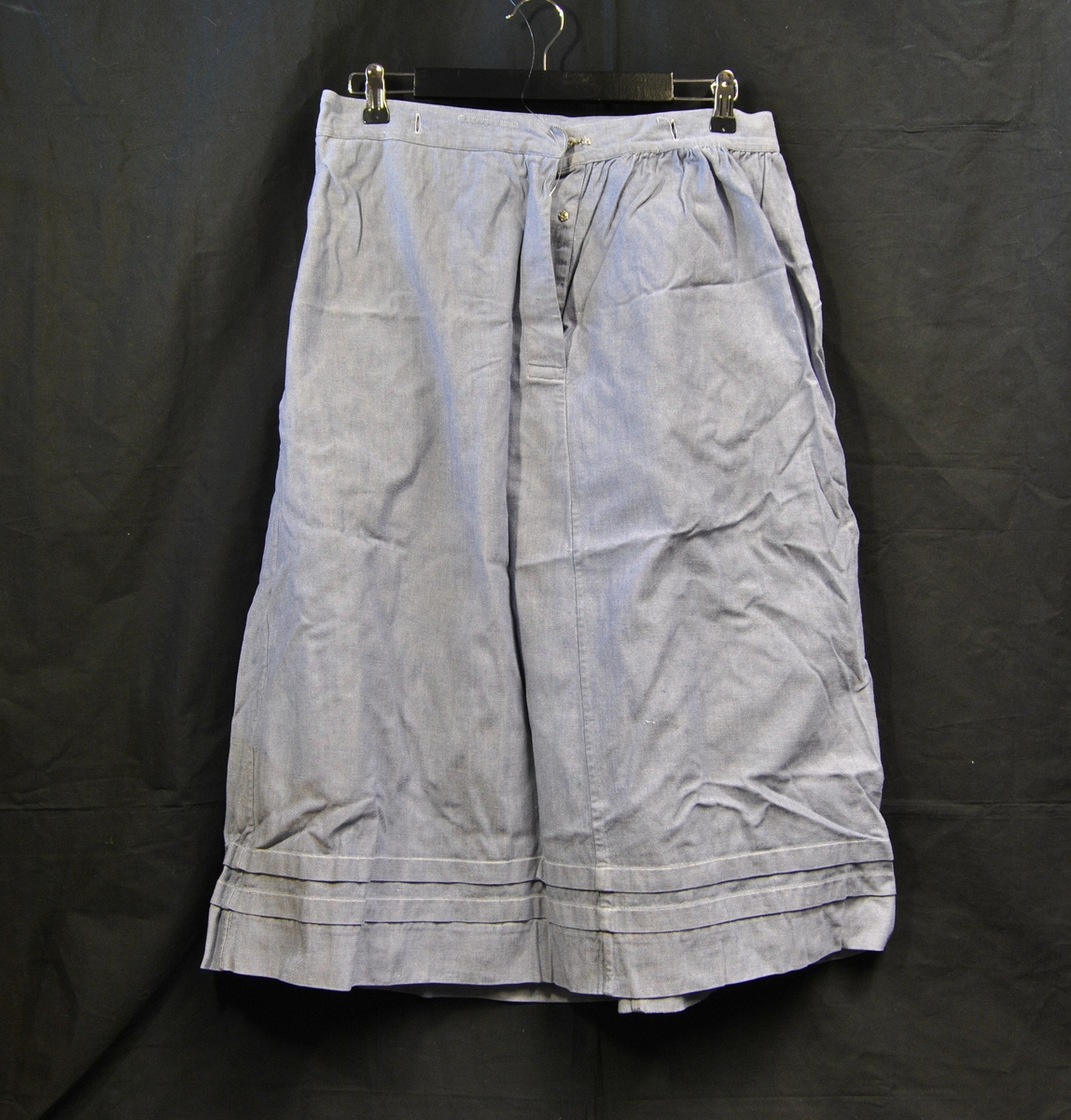 A-formet skjørt med hempe og knepping bak. Knappehull rund linningen.