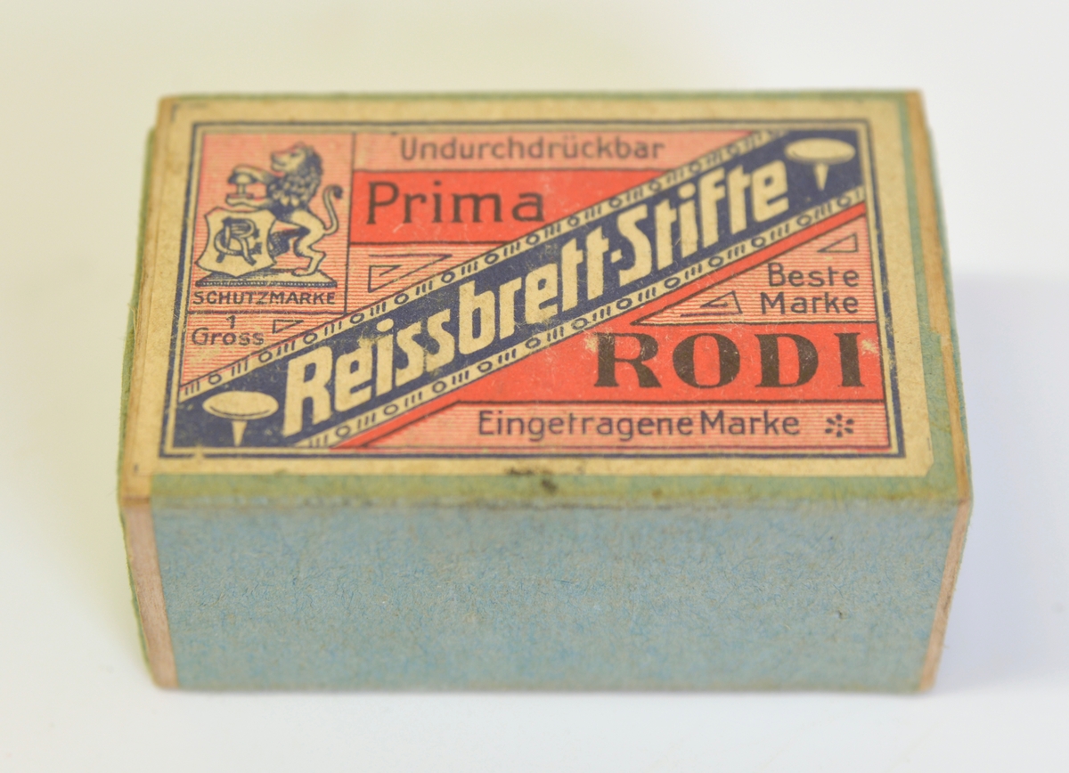 Ser ut som en lite större tändsticksask. Klädd med grönt papper. Etiketten på ovansidan är röd, blå och vit. Tysk text. Har innehållit häftstift.
