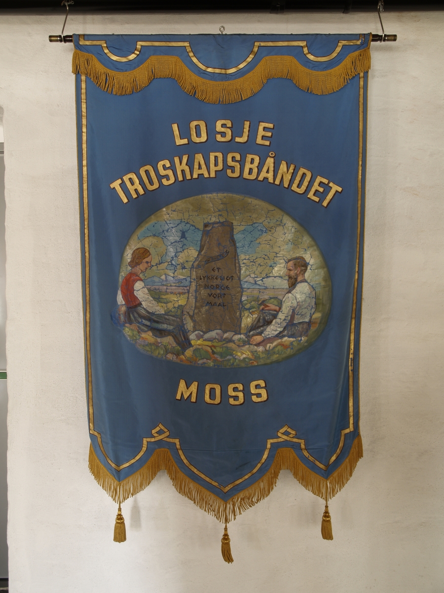 Forside: Kvinne og mann sitter i landskap med bautastein mellom seg. Han er omgitt med verktøy til å hogge i stein. På steinen er følgende innskripsjon: , "DNGTO Et kykkeligt Norge ort maal"., , Bakside: Krans av eikeblader og laubærblader.