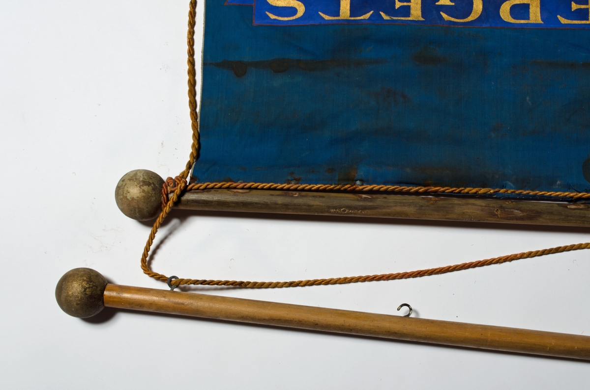 Blå faneduk i bomullslerret med tre korte tunger kantet med frynser nederst. Motiv, påskrift og frynser i gull. 

Framside: Sentrert motiv av Guds lam som bærer korset i sirkel.
Bakside: Sentrert motiv av Guds lam som bærer korset i sirkel.