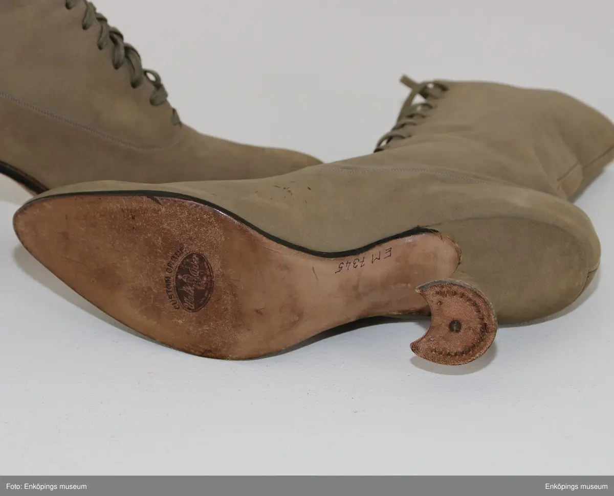 Grönbeige snörkänga för dam av mocka med taxklack.
Tillverkare: Walk Over. Märke: Custom Grade.
Inköpta i Amerika av givarens far Bele Nyström 1916/17. Storlek 38.
