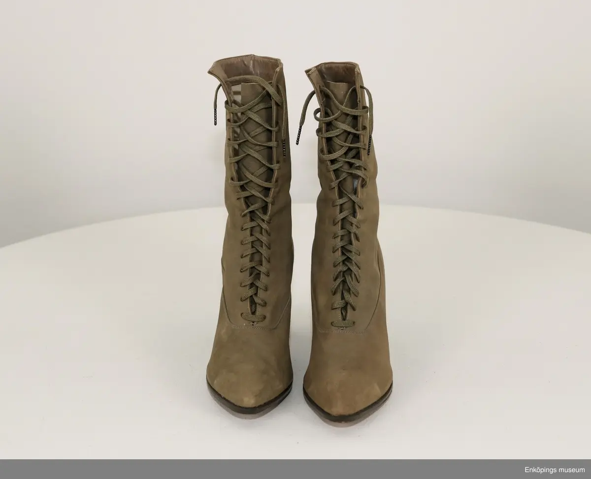 Grönbeige snörkänga för dam av mocka med taxklack.
Tillverkare: Walk Over. Märke: Custom Grade.
Inköpta i Amerika av givarens far Bele Nyström 1916/17. Storlek 38.