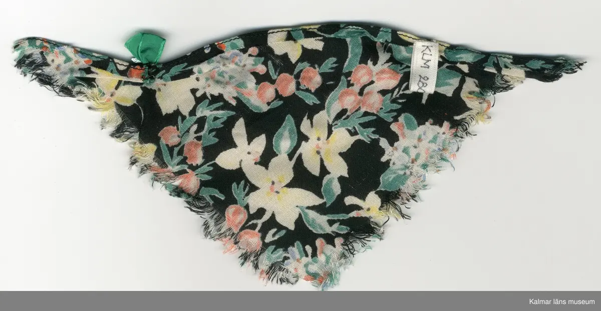 KLM 28082:281:1-4. Dockschal, dam, 4 stycken, del av nationaldräkt, av konstmaterial, med frans, svart botten med blomstermotiv i gult, rött, blått, vitt, grönt, brunt och svart. Knäppes med hake av metall, svart och trådhyska, grön. 
:2 och :3 Schalar, med rosett, grön och brosch, silverfärgad.
