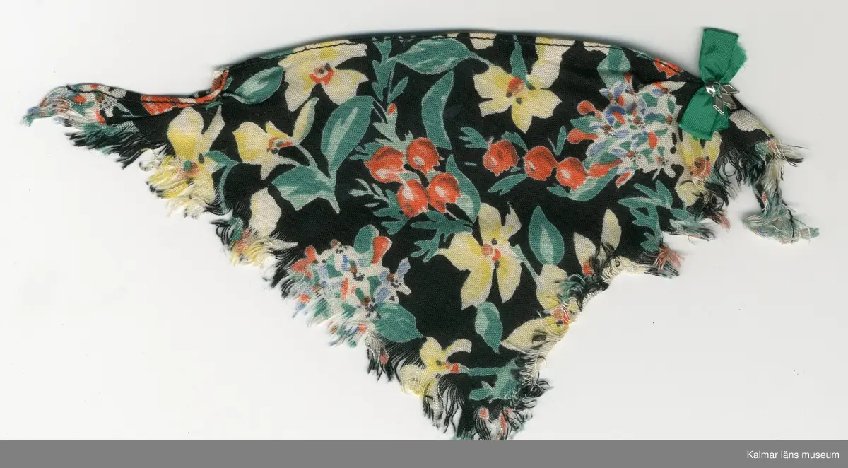 KLM 28082:281:1-4. Dockschal, dam, 4 stycken, del av nationaldräkt, av konstmaterial, med frans, svart botten med blomstermotiv i gult, rött, blått, vitt, grönt, brunt och svart. Knäppes med hake av metall, svart och trådhyska, grön. 
:2 och :3 Schalar, med rosett, grön och brosch, silverfärgad.