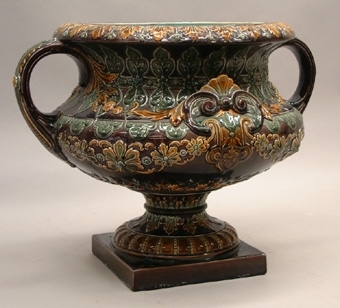 Urna i majolika för blommor. Brun med grön och gul dekor.
Grön inuti.
Rund med två hänklar. Kvadratisk fot.